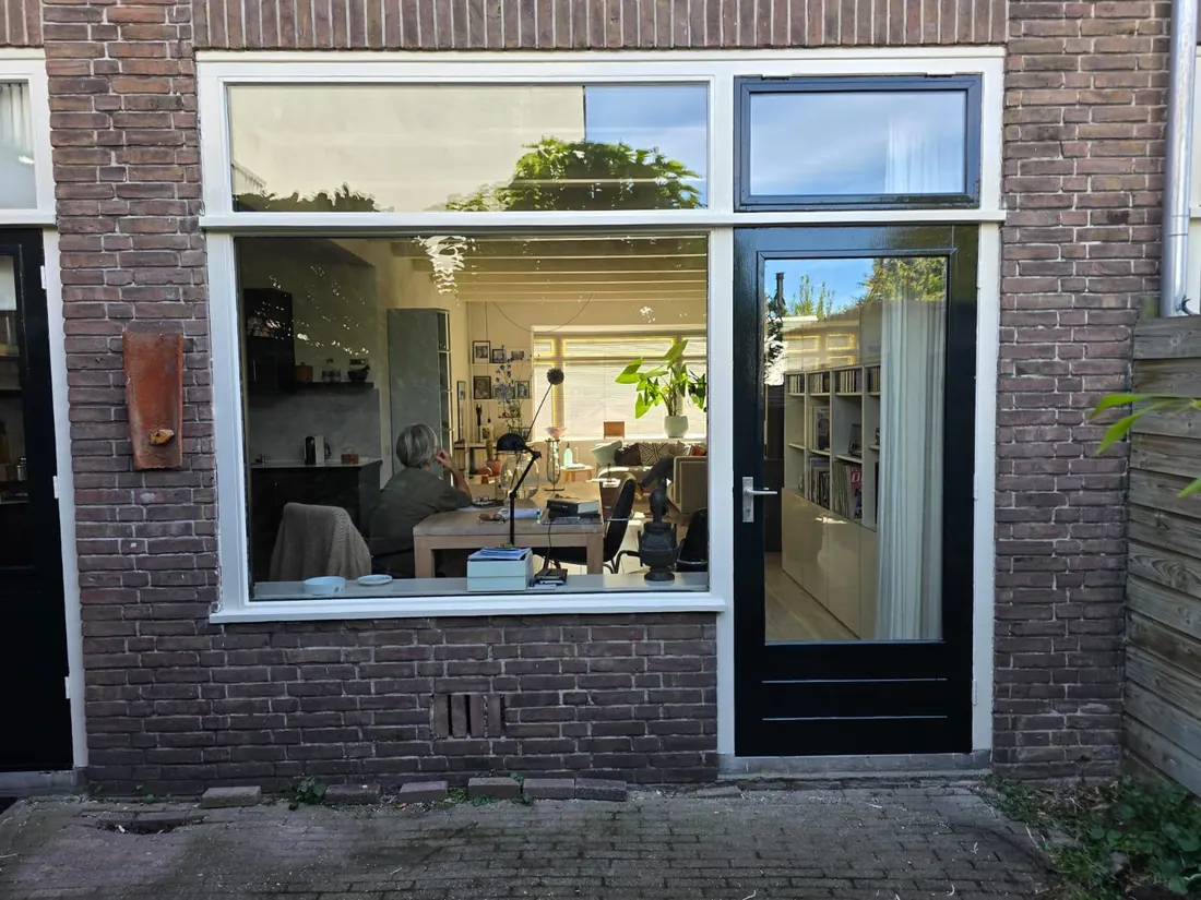 Donkere achterdeur met witte kozijnen aan een tuin