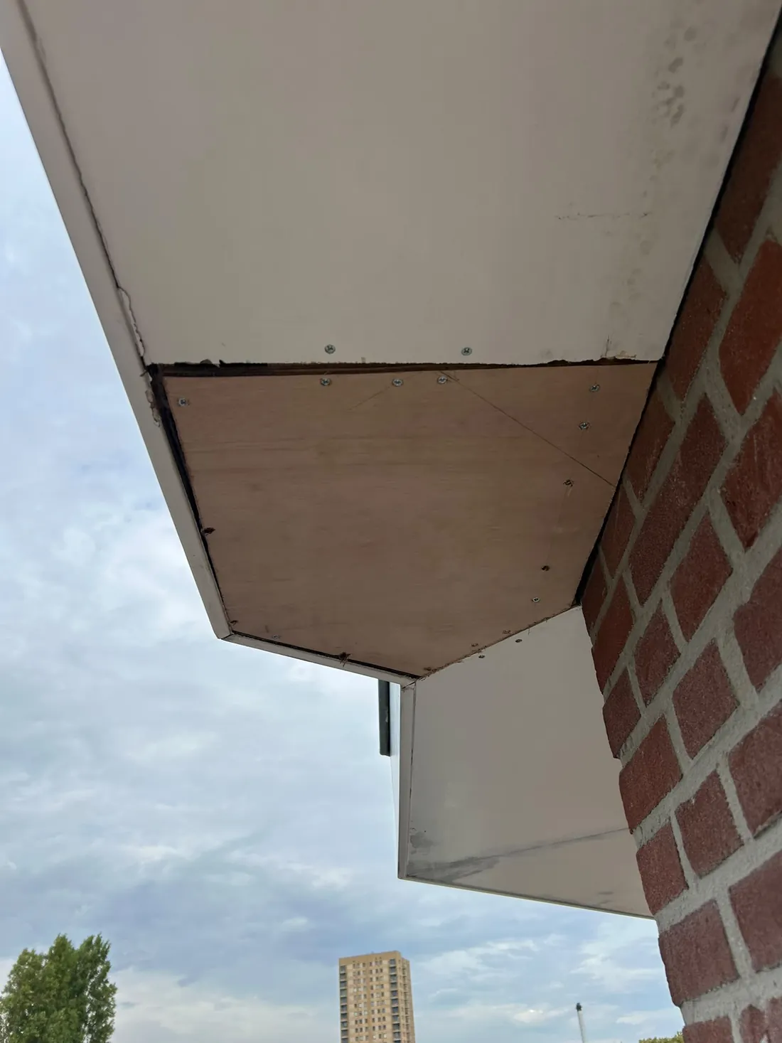 Nieuw houten hoekpaneel in een dakoverstek, bevestigd met schroeven