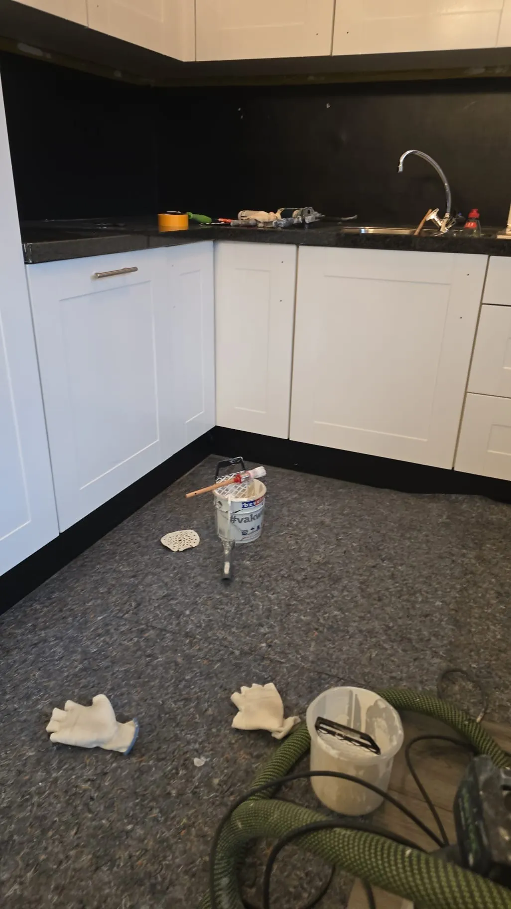 Witte keukenfronten met schildermaterialen op werkblad en vloer