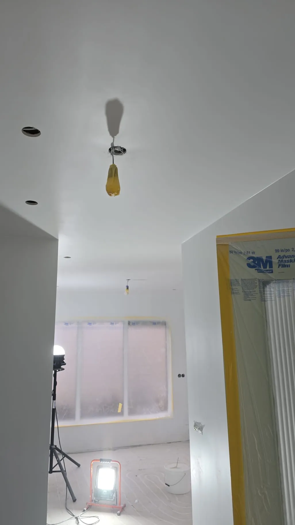 Witte ruimte met afgeplakte ramen, deuren en werkverlichting