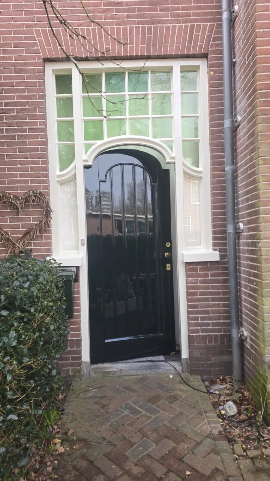 Donkere hoogglans voordeur met een wit sierkozijn