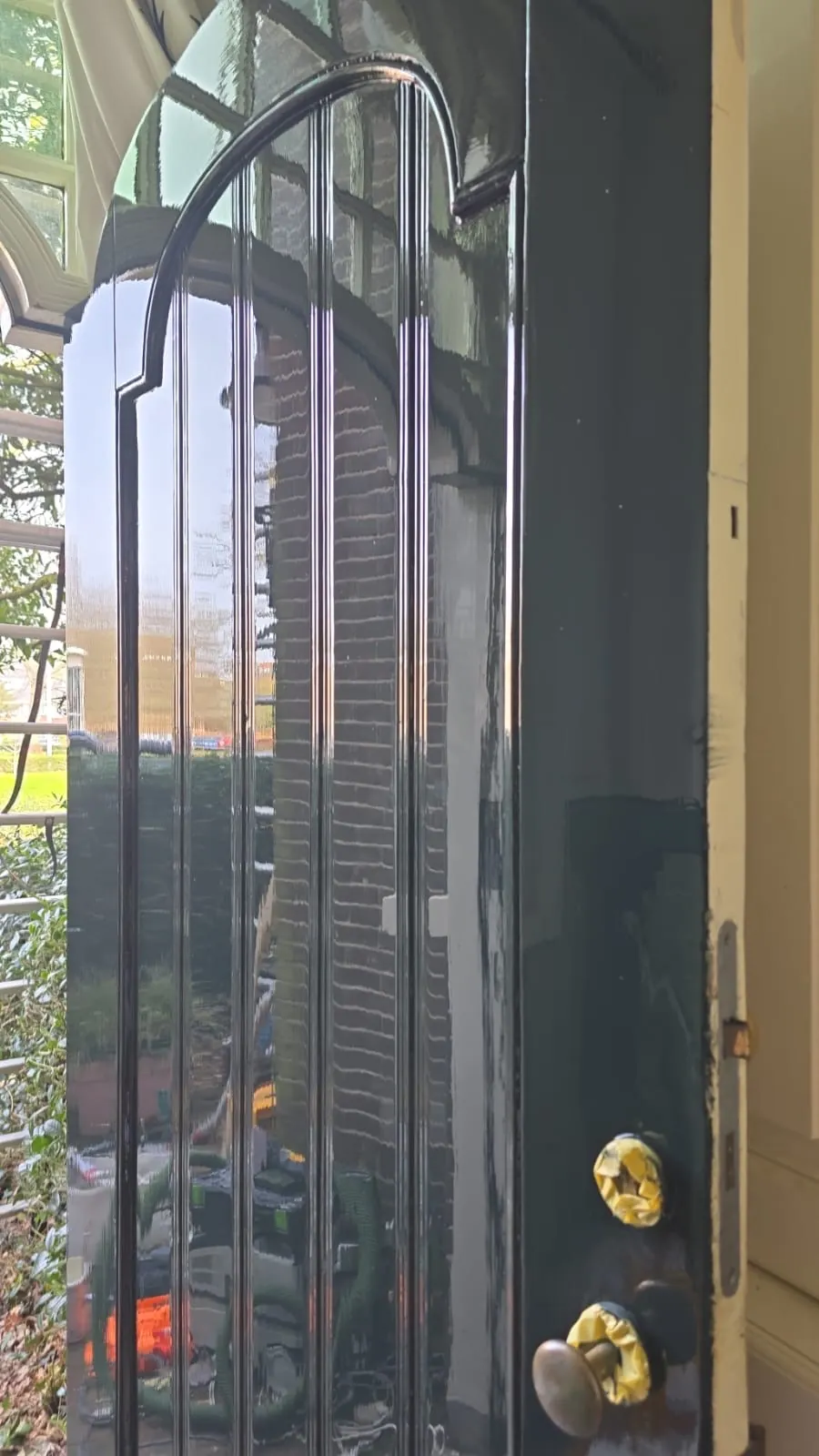 Detail van een donker gelakte voordeur met afgeplakt beslag